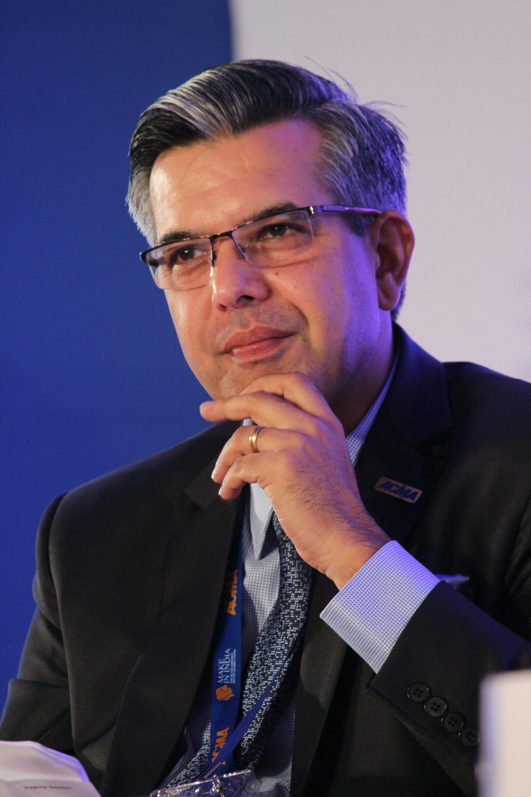 Portrait of a thoughtful businessman in a suit, wearing eyeglasses, captured in an indoor corporate setting.